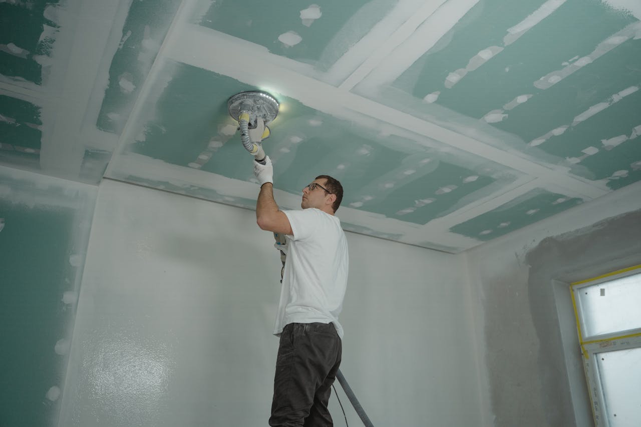Mastering the First Impression: Your intriguing post title goes here A worker expertly polishes a ceiling indoors, demonstrating home renovation skills.