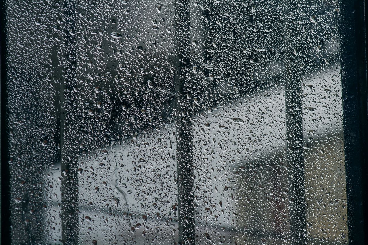 Window Leaks in Singapore – Causes, Rain Ingress Mechanisms and Diagnosis Close-up of rain-soaked window with water droplets, creating a moody and cool atmosphere.